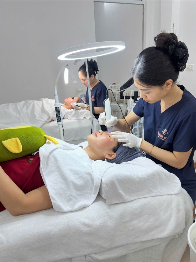 Kỹ thuật viên chăm sóc da mặt cho khách bằng thiết bị chuyên dụng