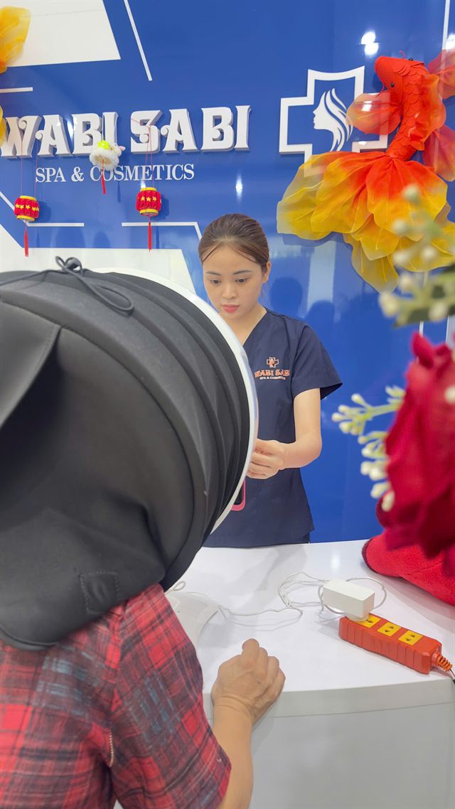 Khách soi da bằng máy 5D trước bức tường logo Wabi Sabi